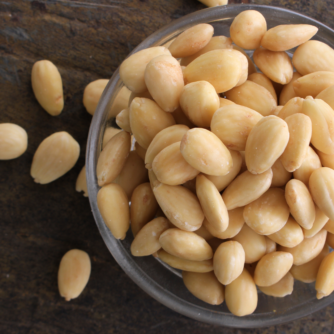 Glass bowl filled with pine nuts on a dark surface