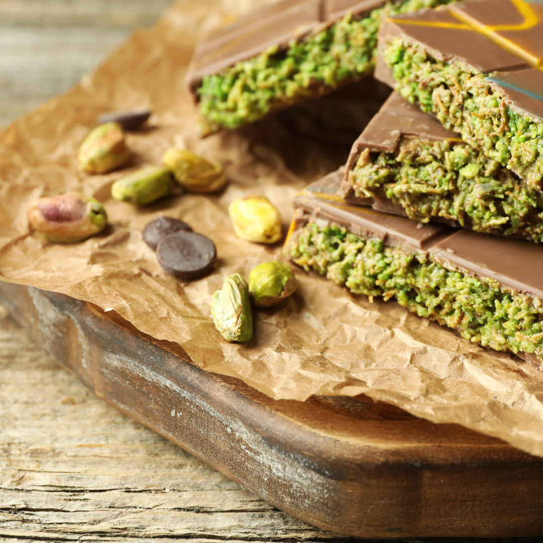 Chocolate bars with green pistachio topping on a wooden board, branded 'Snack n Dash'.