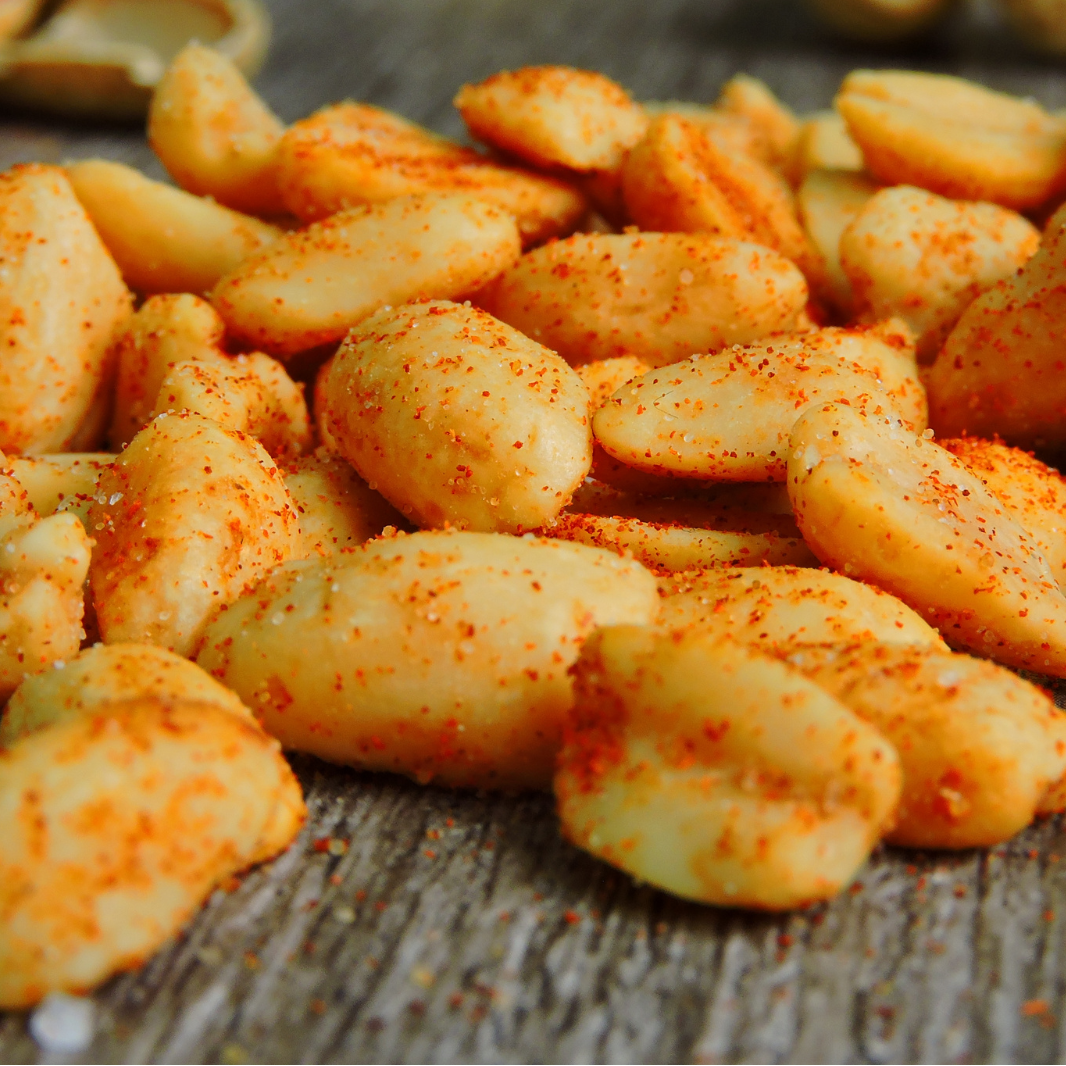 Spiced peanuts on a wooden surface with 'Snack n Dash' branding.