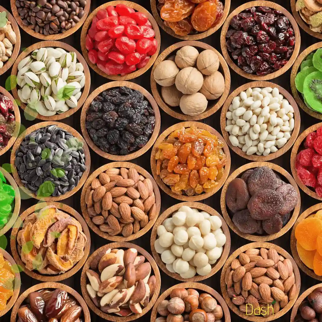 A top-down grid of small round wooden bowls filled with assorted dried fruits, nuts, seeds, and green flakes on a dark background. A small 'Dash' logo appears in the bottom-right corner.